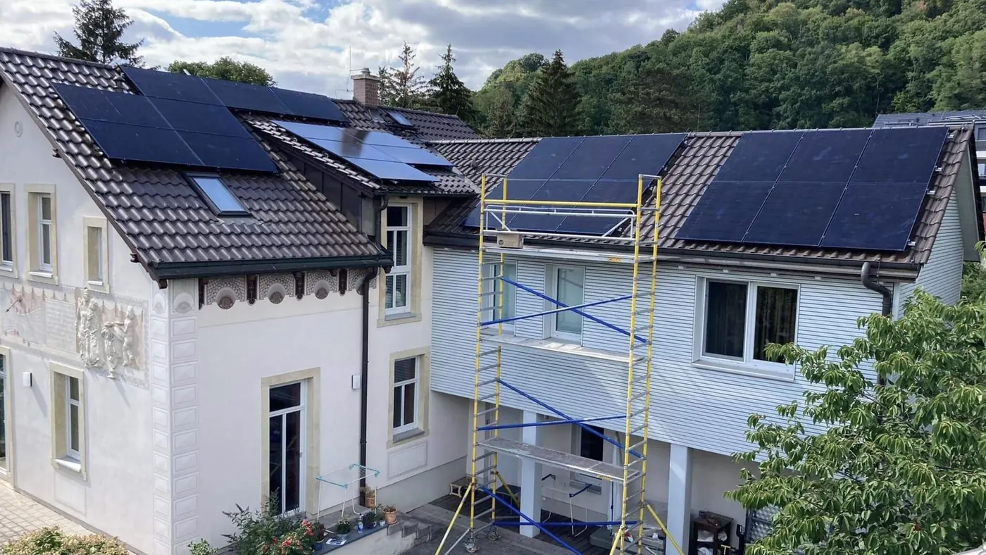 Wohnhaus mit montierter PV-Anlage auf dem Ziegeldach und Gerüst an der Fassade